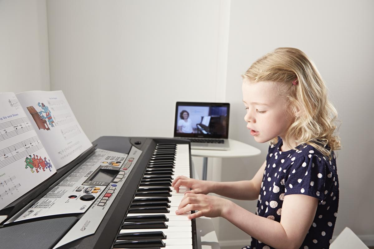 Picture of a child learning piano remotely with a teacher